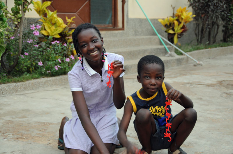 Esi and Joseph play with a barrel of monkeys